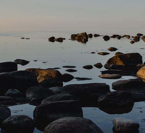 A serene scene with smooth stones and calm water reflecting light.